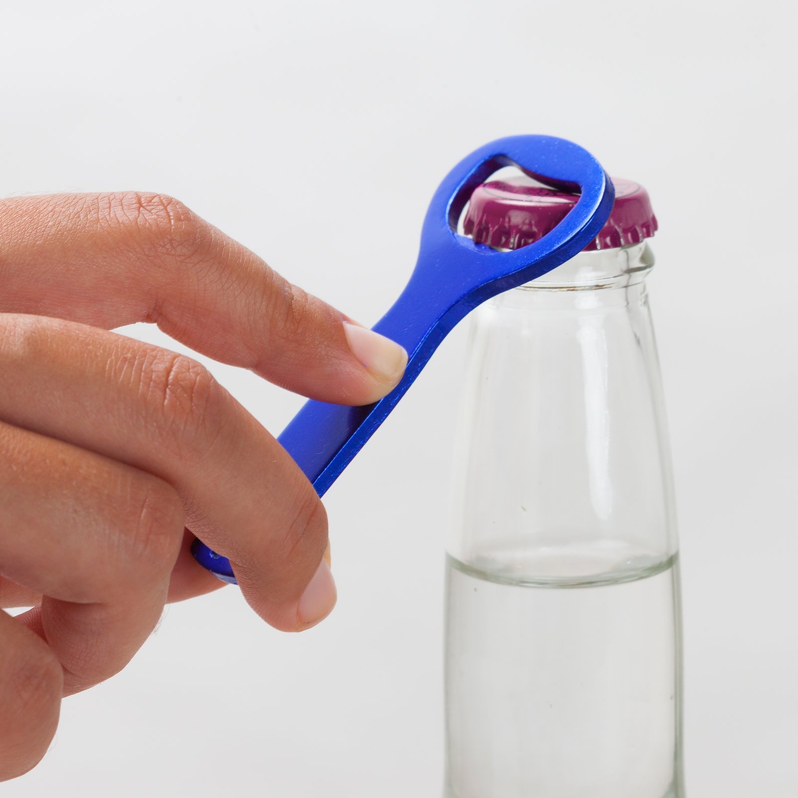 Persona usando abridor de botellas para abrir una botella de lager.