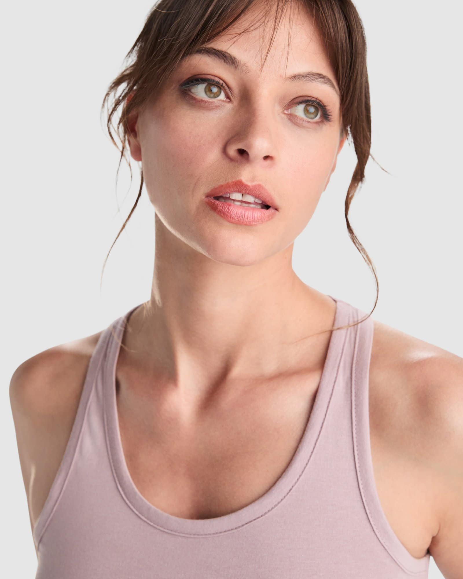 MUGYNOX - Mujer con camiseta rosa y pantalones beige en estudio Mujer con camiseta rosa, mirada pensativa, en estilo natural y elegante.